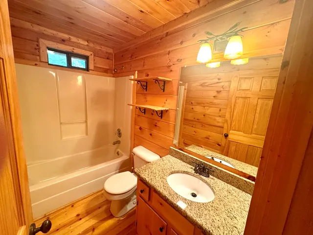 a bathroom with a granite countertop sink toilet and shower