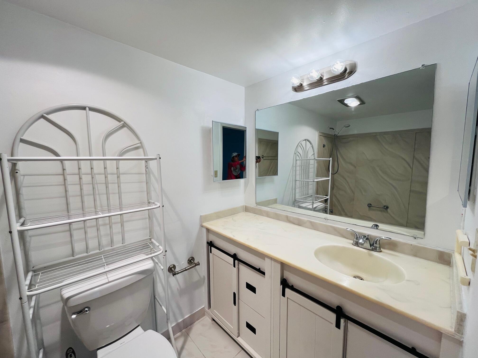 2600 Southwest 22nd Avenue, Unit 903 Delray Beach, FL 33445 - Photo 6 of 27 a bathroom with a sink a toilet and a mirror