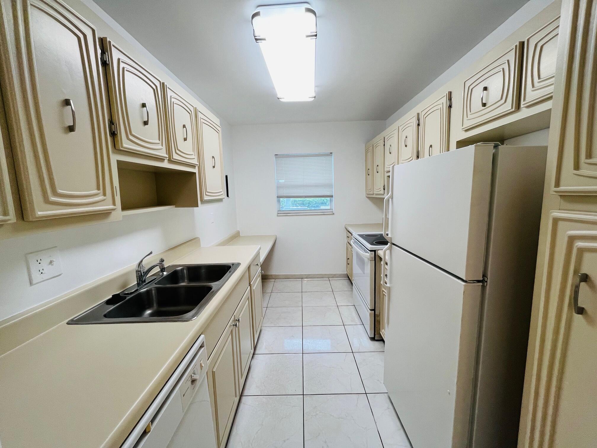 2600 Southwest 22nd Avenue, Unit 903 Delray Beach, FL 33445 - Photo 9 of 27 a kitchen with a refrigerator and a sink