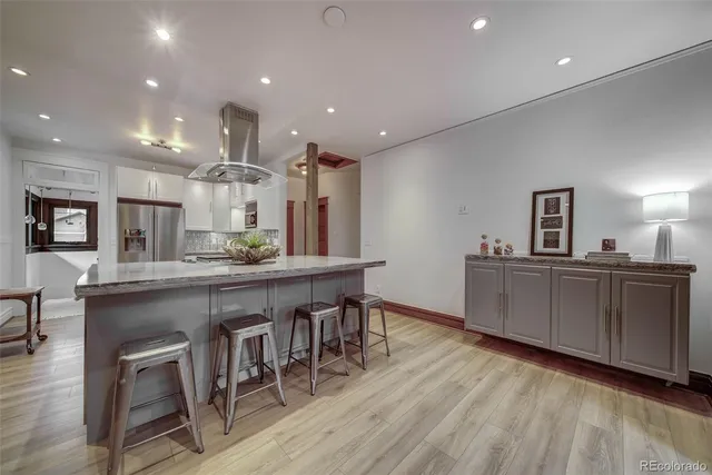 a kitchen with stainless steel appliances a dining table chairs and wooden floor
