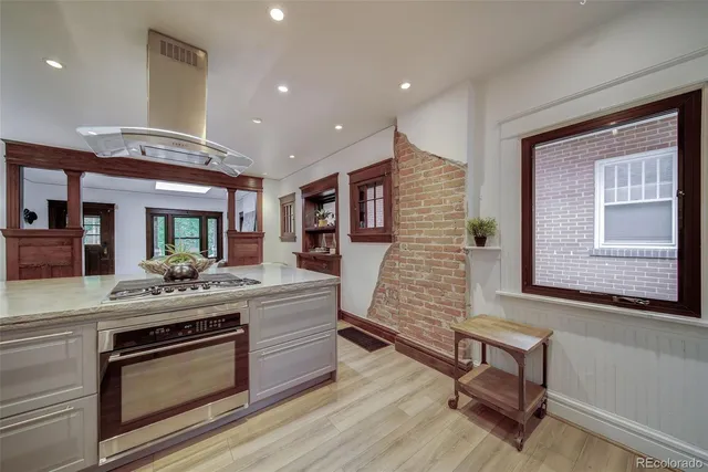 a view of living room kitchen with stainless steel appliances wooden floor and stove