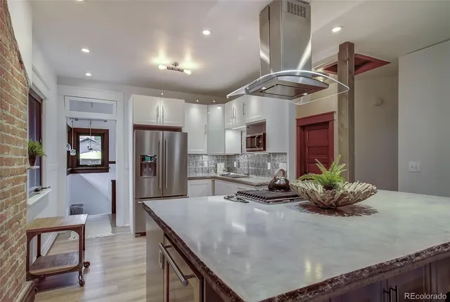 a kitchen with stainless steel appliances kitchen island granite countertop a table chairs in it and wooden floors