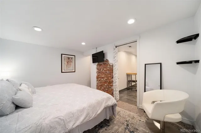 a spacious bedroom with a bed a chair and a large mirror