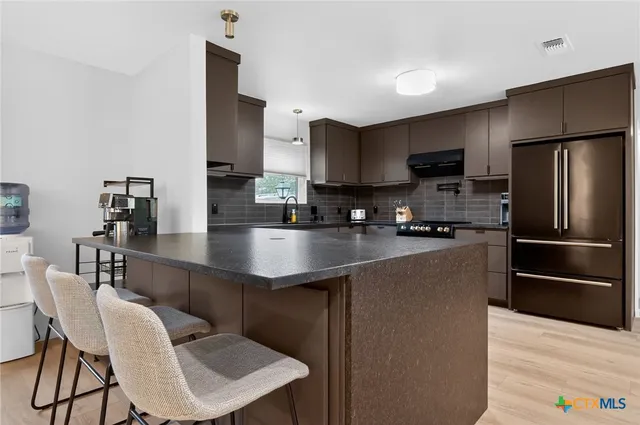 a kitchen with kitchen island granite countertop a sink cabinets and stainless steel appliances