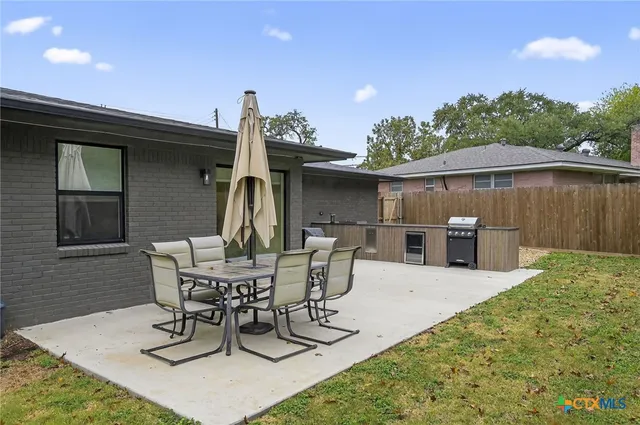 a view of a patio with table and chairs and potted plants with wooden fence