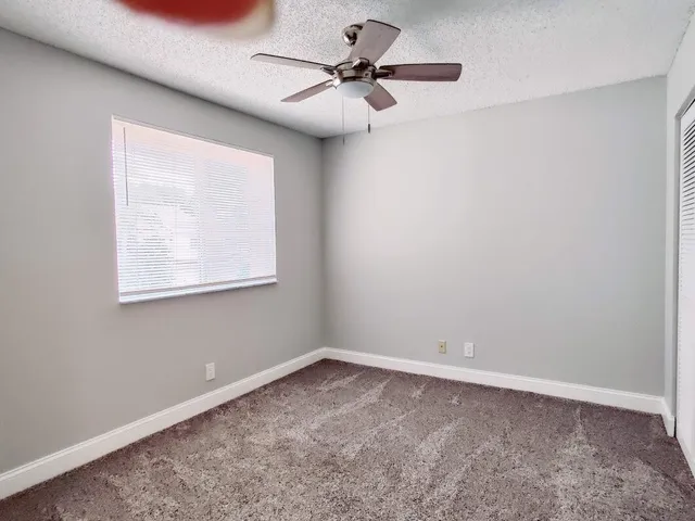 an empty room with a window and a fan