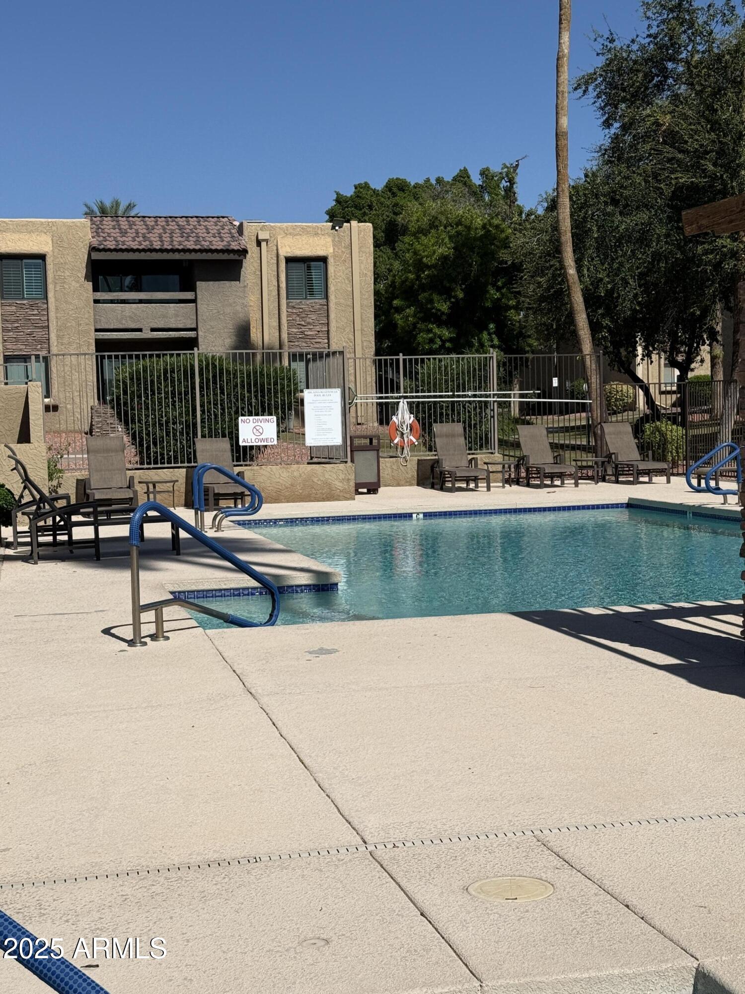 3825 East Camelback Road, Unit 120 Phoenix, AZ 85018 - Photo 35 of 39 a view of a swimming pool with a bench and lawn chairs