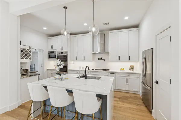 a kitchen with stainless steel appliances a dining table chairs sink and cabinets