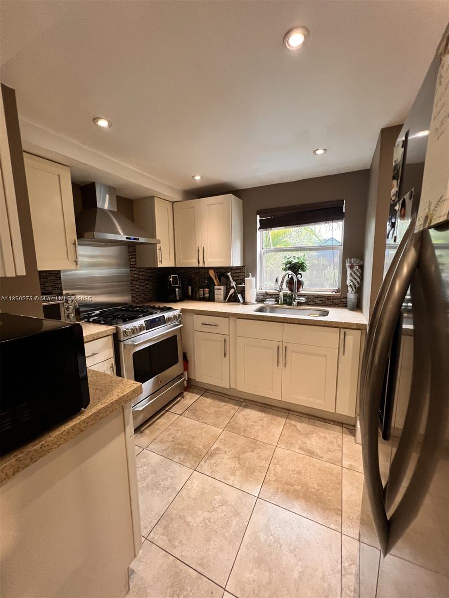 11394 Southwest 65th Street, Unit 1 Miami, FL 33173 - Photo 9 of 9 a kitchen with stainless steel appliances kitchen island granite countertop a sink a stove top oven and cabinets