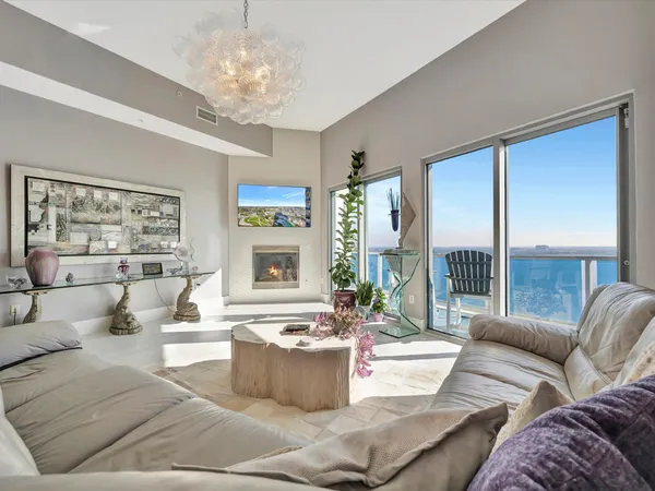 a living room with furniture kitchen view and a chandelier