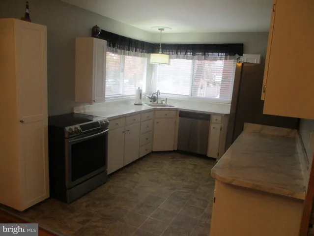 a kitchen with stainless steel appliances granite countertop white cabinets and window