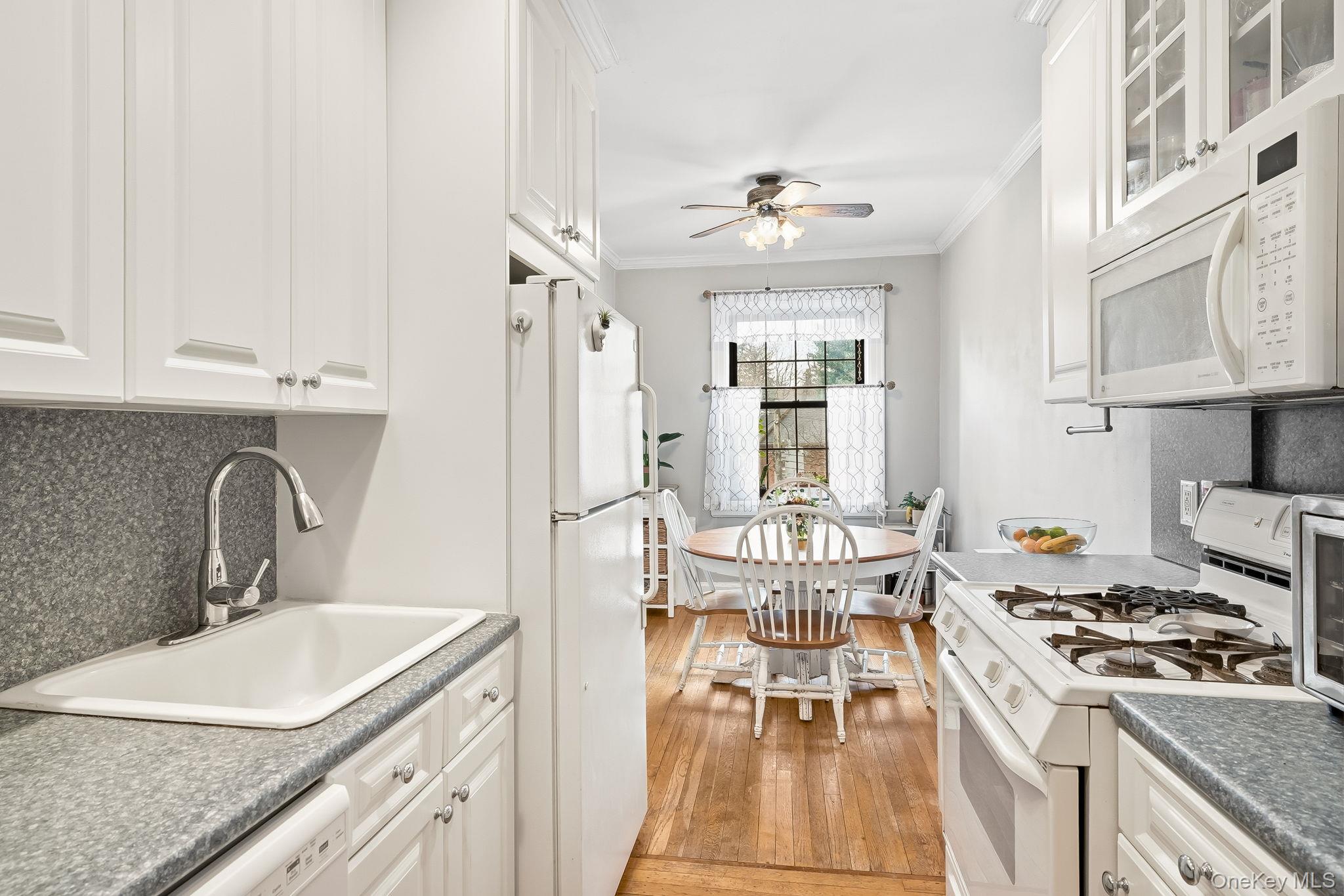 23 Old Mamaroneck Road, Unit 3L White Plains, NY 10605 - Photo 7 of 16 Kitchen with tasteful backsplash, white appliances, white cabinets, ornamental molding, and light wood-style flooring