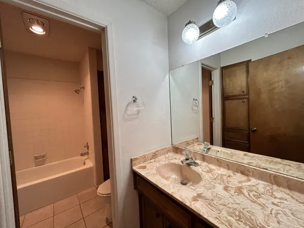 a bathroom with a granite countertop sink a toilet and shower