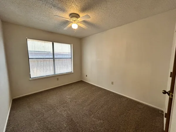 an empty room with windows and chandelier fan