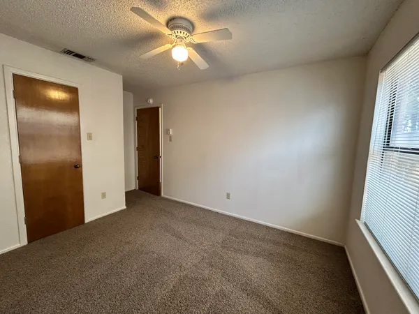 an empty room with windows and fan