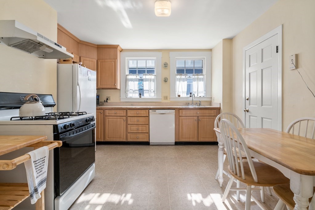 18 Fairfax Road Milton, MA 02186 - Photo 18 of 30 a kitchen with stainless steel appliances granite countertop a stove top oven a sink a dining table and chairs with wooden floor