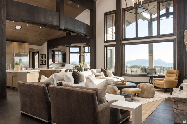 9156 Forest Road, Unit 24 Heber City, UT 84036 - Photo 3 of 42 Great room featuring soaring ceilings with exposed dark wood beams, expansive windows, wood-finish flooring, and a stone-clad fireplace