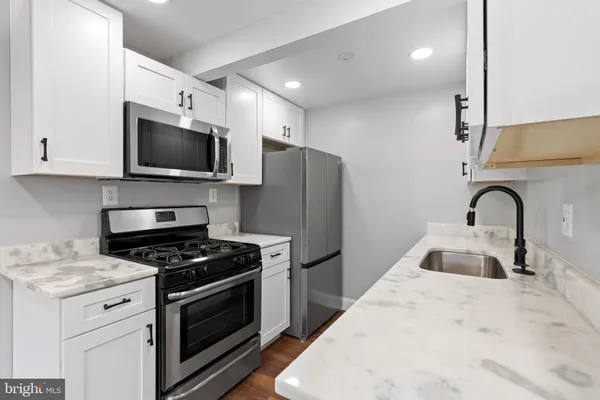 a kitchen with granite countertop a sink stainless steel appliances and cabinets