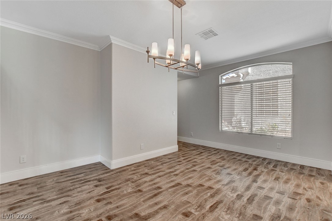 191 Verde Ridge Court Henderson, NV 89012 - Photo 5 of 36 Spare room featuring wood finished floors, crown molding, a chandelier, and baseboards