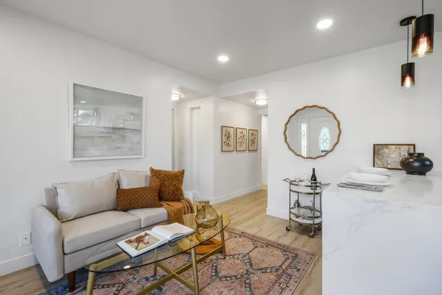 a living room with furniture a mirror and wooden floor
