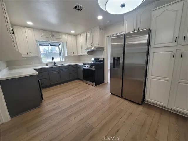 a kitchen with stainless steel appliances granite countertop a refrigerator a sink a stove a microwave and with wooden floors