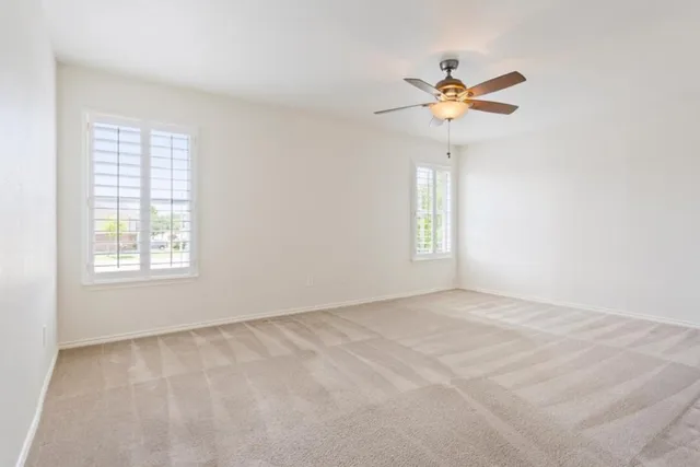 an empty room with a window and a fan
