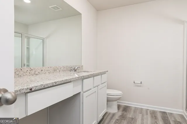 a bathroom with a granite countertop sink a toilet and a mirror