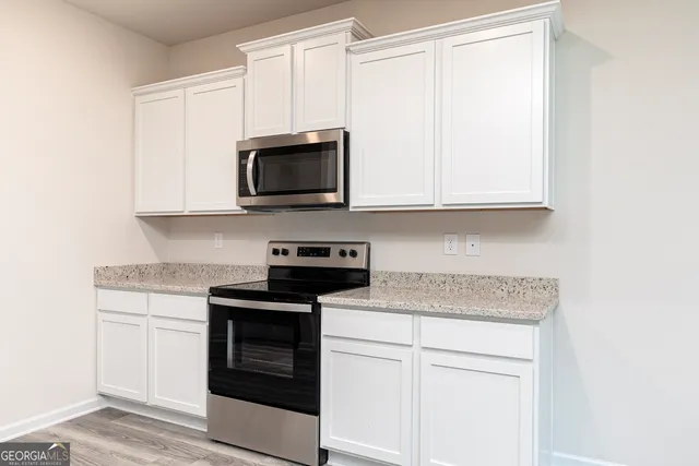 a kitchen with stainless steel appliances granite countertop white cabinets and a stove top oven