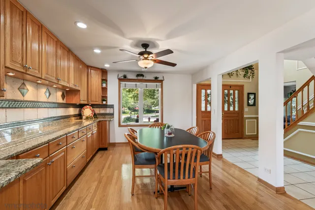 a kitchen with a dining table chairs stainless steel appliances cabinets and a window