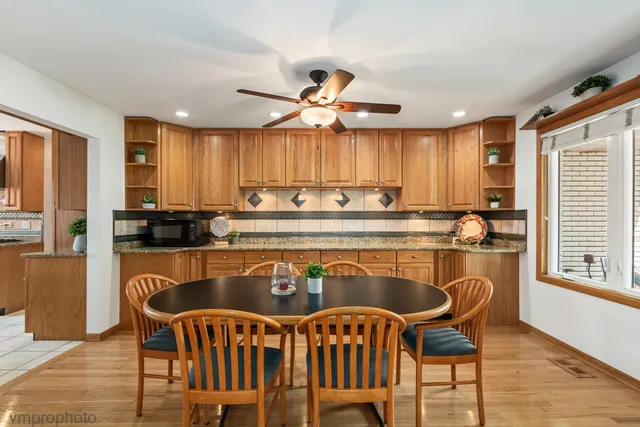 a kitchen with stainless steel appliances granite countertop a stove top oven a sink dishwasher a dining table and chairs with wooden floor