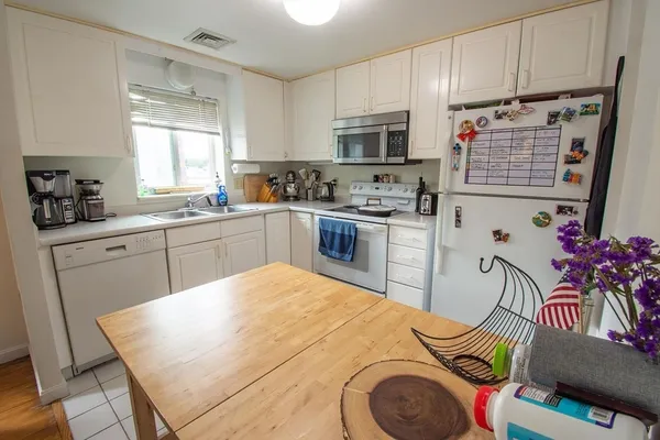 a kitchen with stainless steel appliances granite countertop a sink dishwasher stove and white cabinets with wooden floor