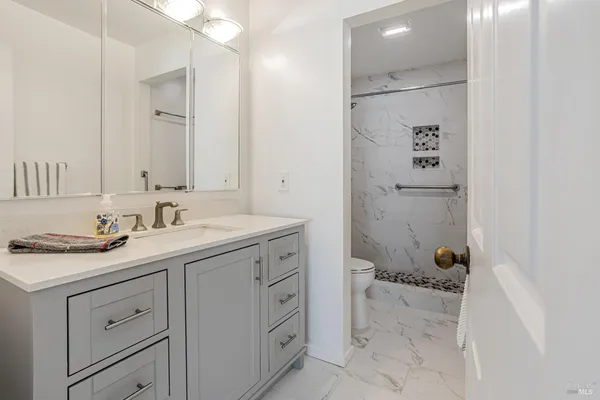 a bathroom with a granite countertop sink mirror and toilet