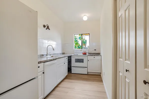 a kitchen with white cabinets and sink