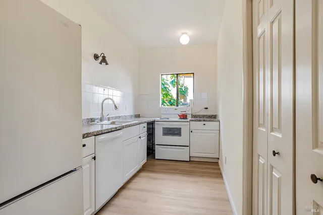 a kitchen with white cabinets and sink