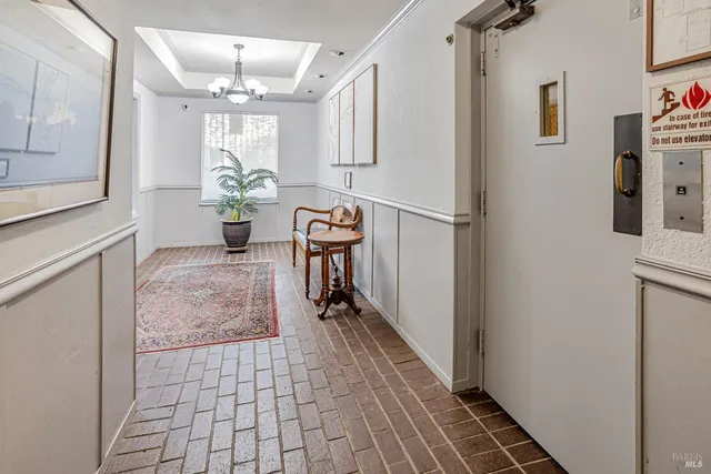 a hallway with wooden floor and chandelier