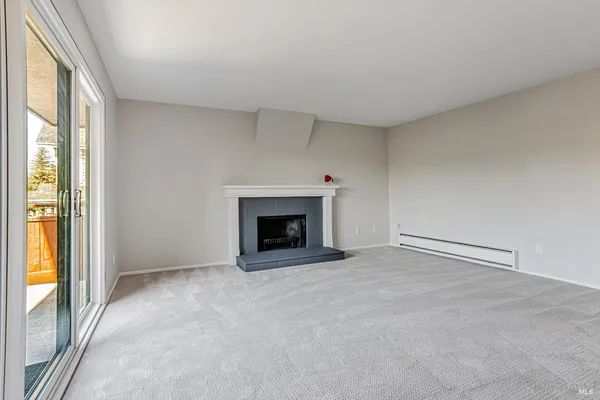 a view of an empty room with a window and a fireplace