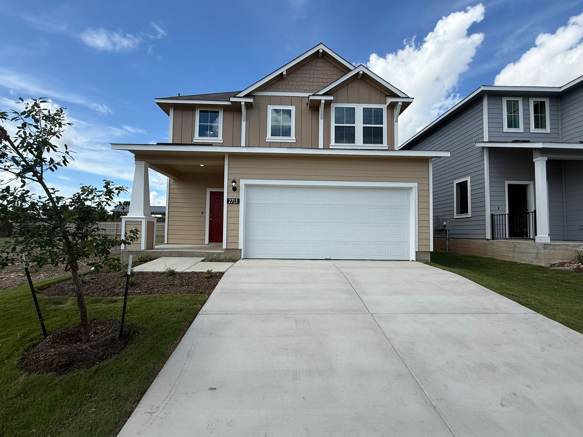 View of front of home featuring board and batten siding, a garage, concrete driveway, and a front yard