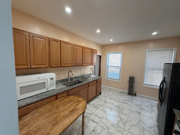 a large kitchen with kitchen island granite countertop a refrigerator and a stove top oven