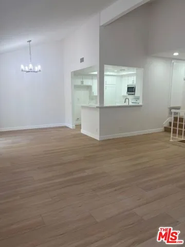 a view of kitchen and empty room with wooden floor