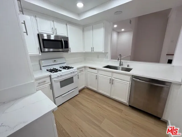 a kitchen with white cabinets stainless steel appliances and sink