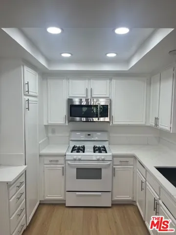 a kitchen with stainless steel appliances white cabinets and white appliances