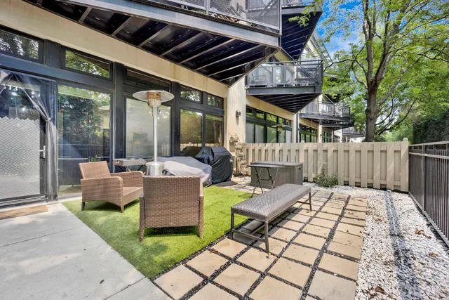 a view of a patio with couches table and chairs and wooden fence