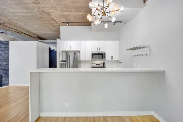 a view of a kitchen with kitchen island a sink stainless steel appliances and cabinets