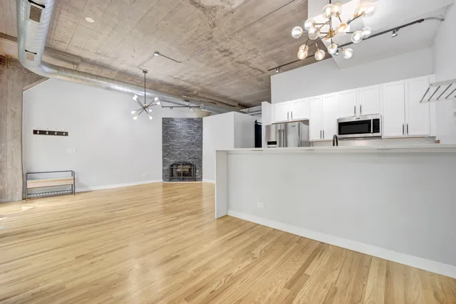 a view of a kitchen with kitchen island wooden floor and stainless steel appliances