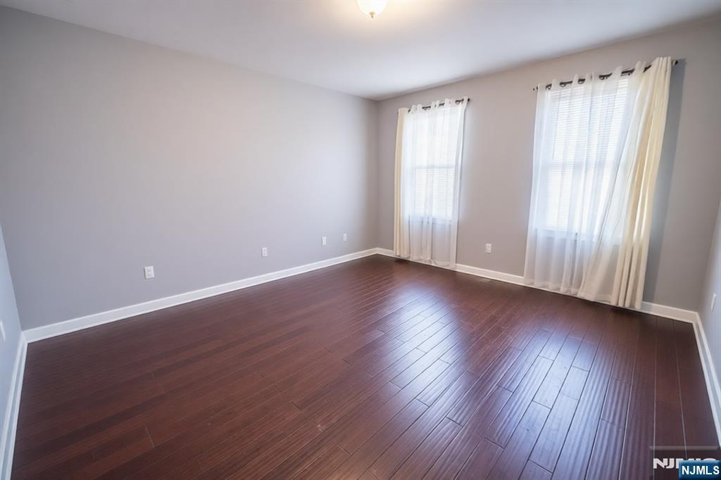 289 Rose Street Newark, NJ 07108 - Photo 14 of 29 an empty room with wooden floor and windows with curtains view