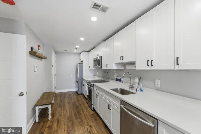 a kitchen with a sink a counter top space stainless steel appliances and cabinets
