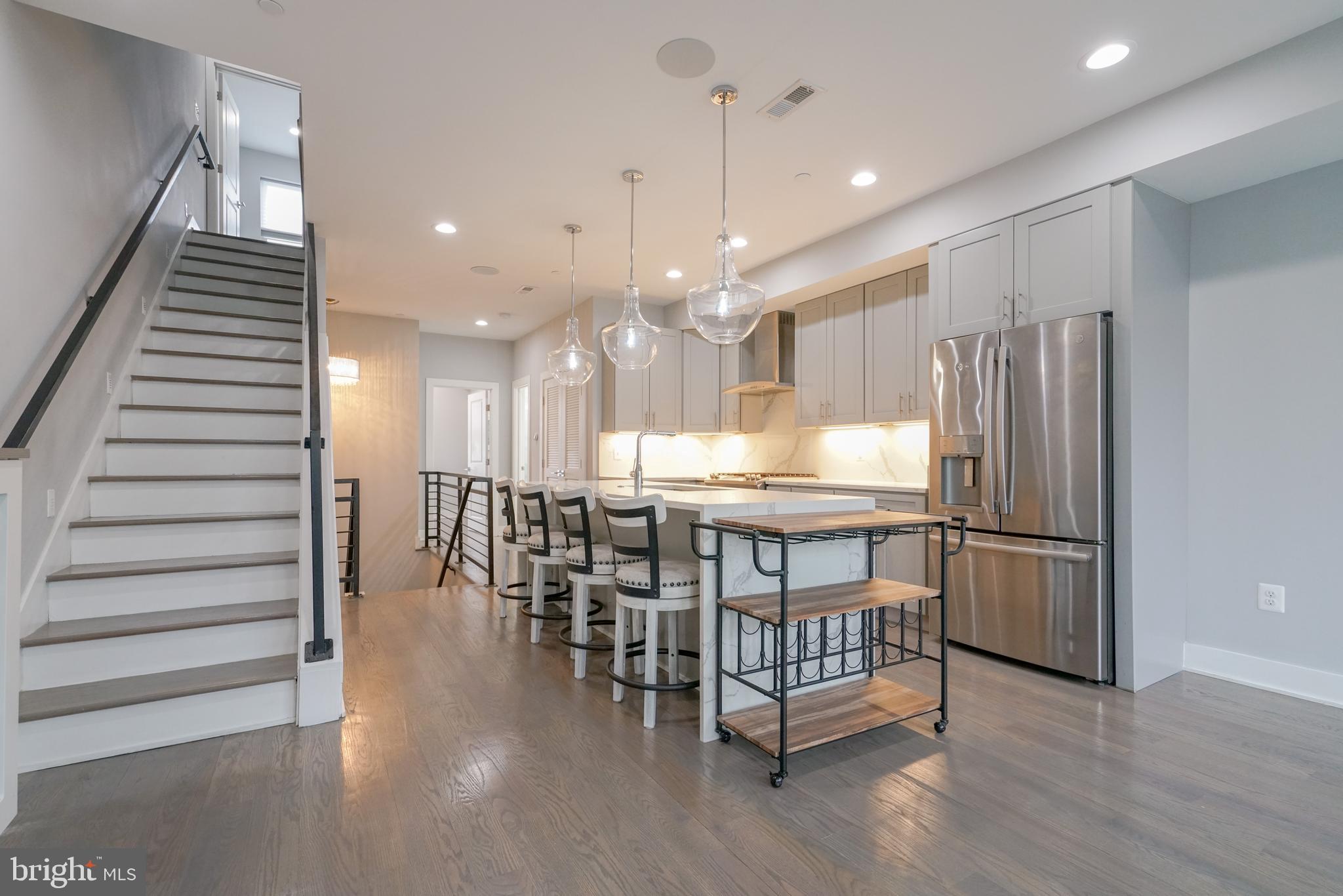 1632 K Street Northeast, Unit PH Washington, DC 20002 - Photo 6 of 69 a kitchen with stainless steel appliances kitchen island granite countertop a table chairs and a refrigerator