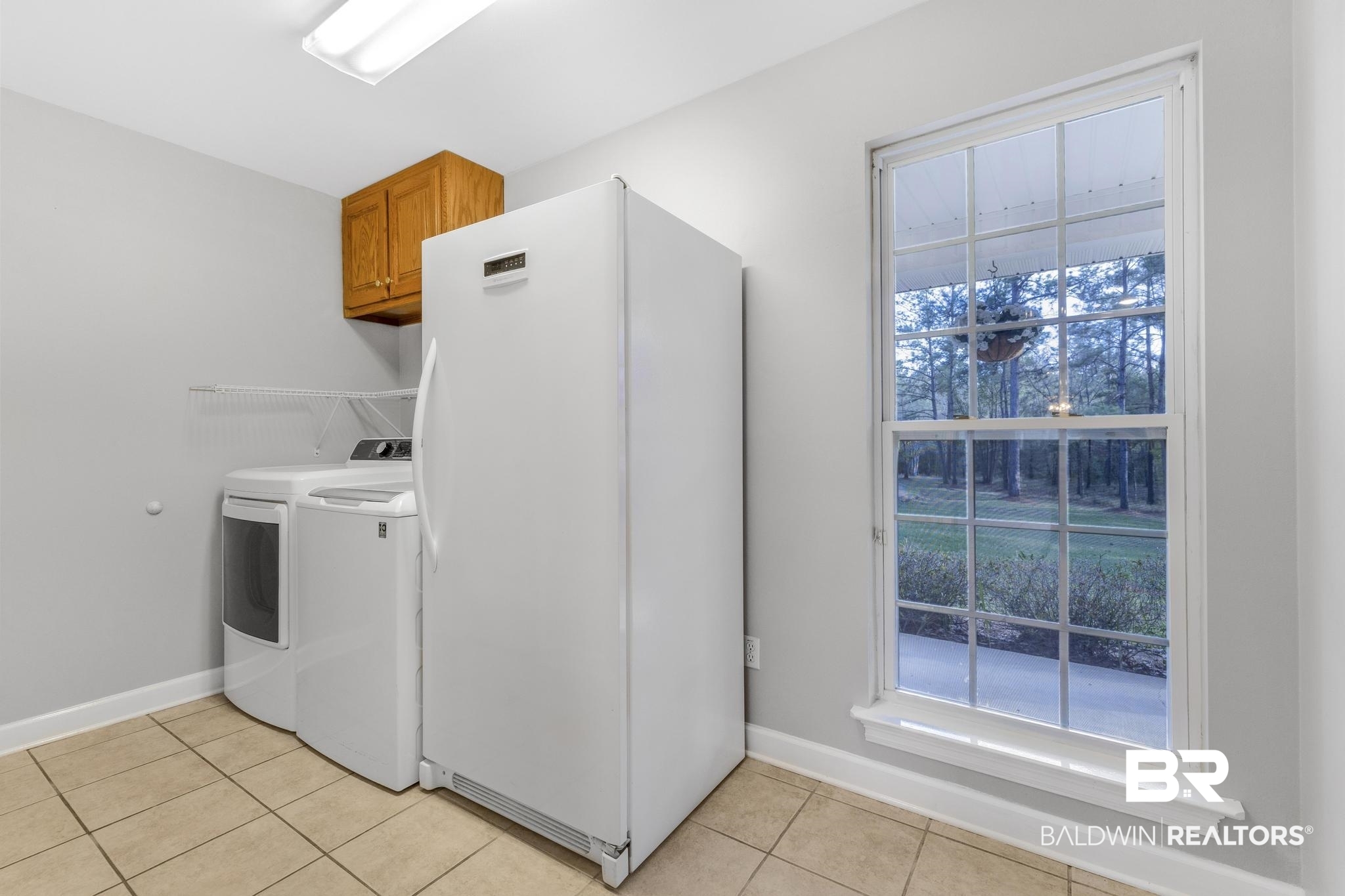 8077 Hooks Road Bay Minette, AL 36507 - Photo 17 of 48 Laundry room featuring washing machine and clothes dryer, light tile patterned flooring, and cabinet space