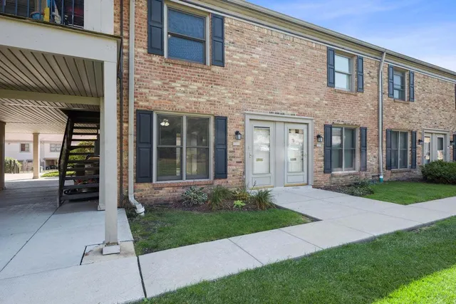 a view of a brick house with a yard and large tree