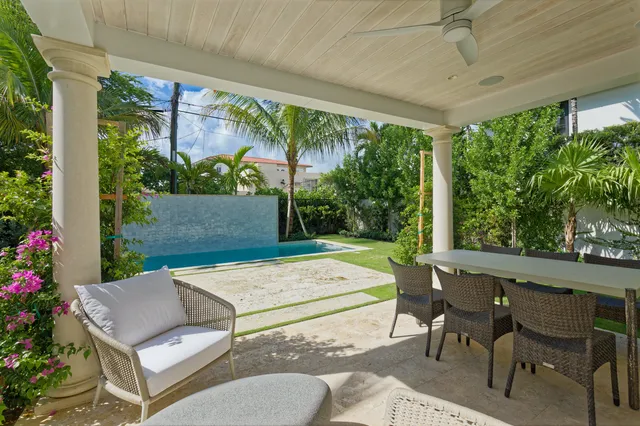 a view of a patio with table and chairs potted plants and floor to ceiling window